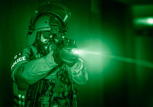 An operator of a special police unit with night vision googles firing with a pistol.