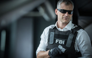 An FBI officer with a pistol at the ready.