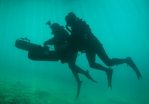 Two Special Operations Forces combat diver with diver propulsion vehicle.