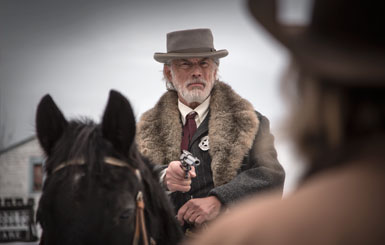 A marshal on his horse with his revolver at the ready.