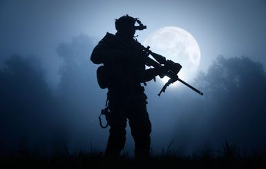 A sniper with night vision goggles and sniper rifle in the moonlight.